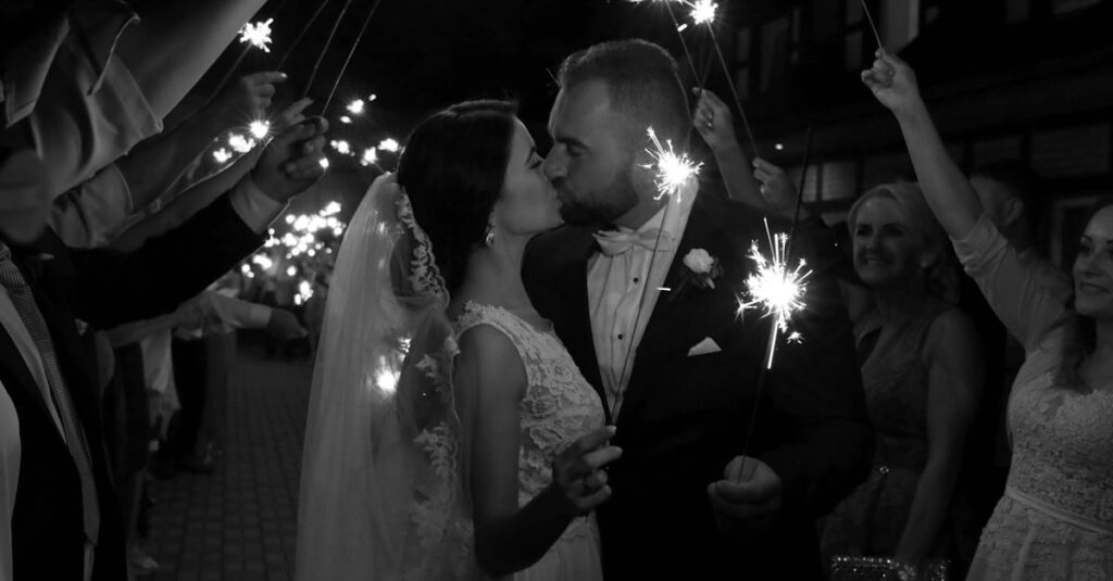 Bride and groom share a romantic kiss with sparklers, creating a magical wedding moment.