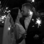 Bride and groom share a romantic kiss with sparklers, creating a magical wedding moment.