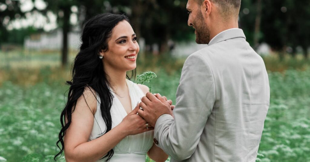 A lovely couple in elegant attire sharing a joyful moment outdoors in a lush garden setting.