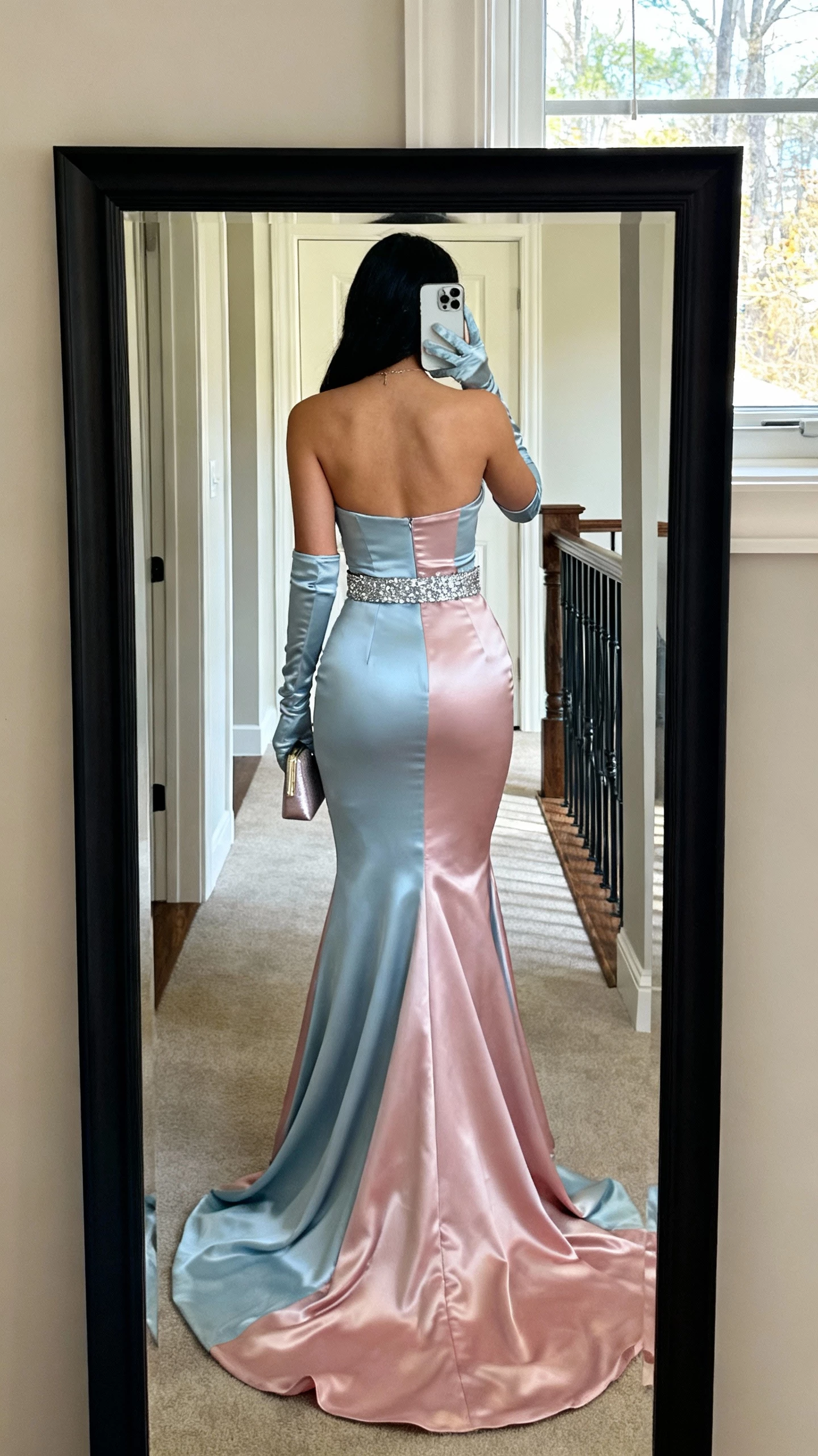 iPhone back-view mirror selfie of a woman in a two-tone mermaid gown with matching satin gloves and a sparkly belt cinching the waist, small clutch, face not visible, entryway full-length mirror, natural daylight, natural iPhone photo quality.