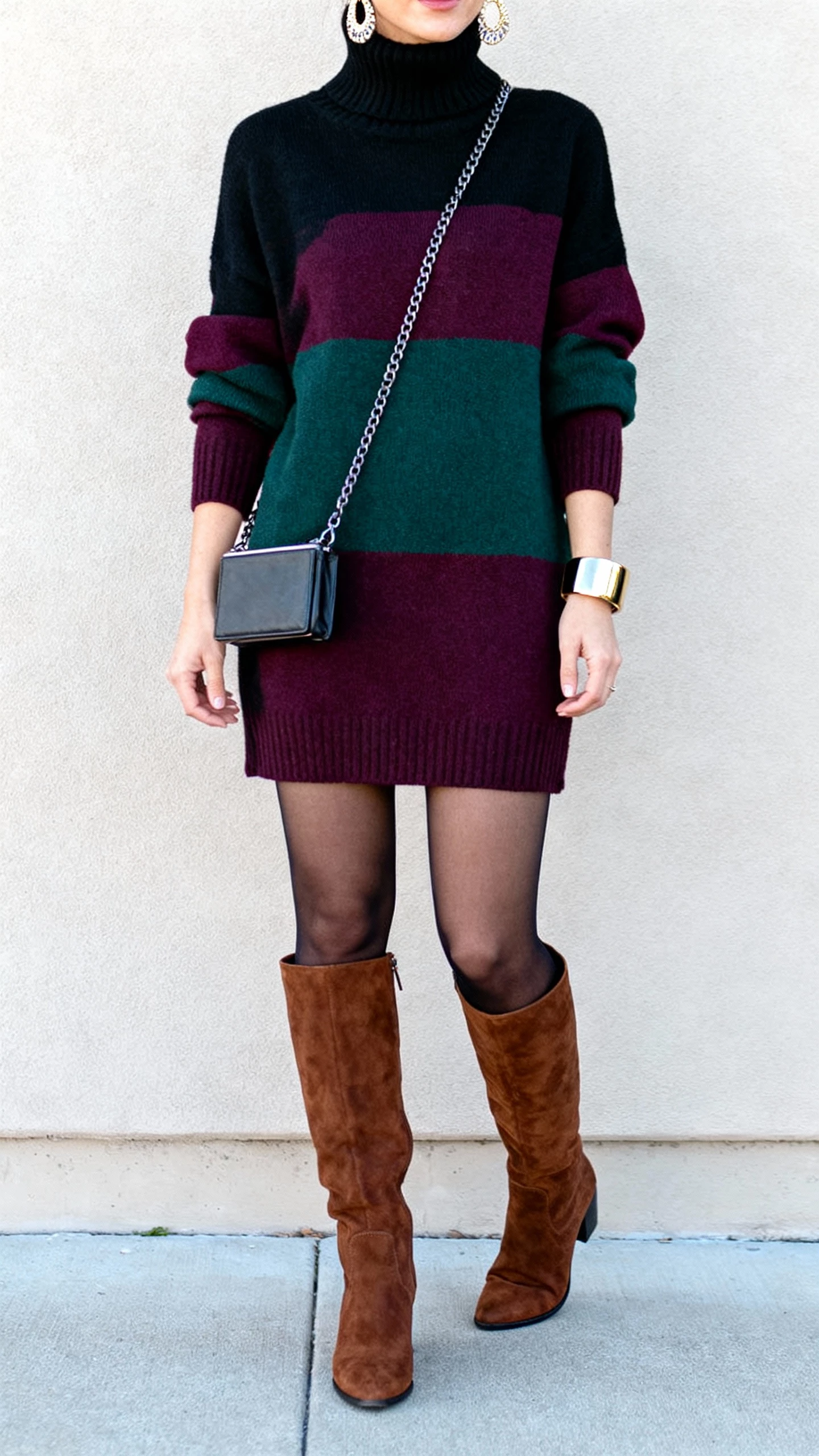 iPhone hallway mirror selfie of a woman wearing a turtleneck mini sweater dress (black/deep plum/pine) with suede or leather over-the-knee boots (flat or mid-heel), optional opaque tights, compact crossbody with chain strap, statement earrings or bold cuff bracelet; face not visible, cropped at shoulders, natural daylight, natural iPhone photo quality.