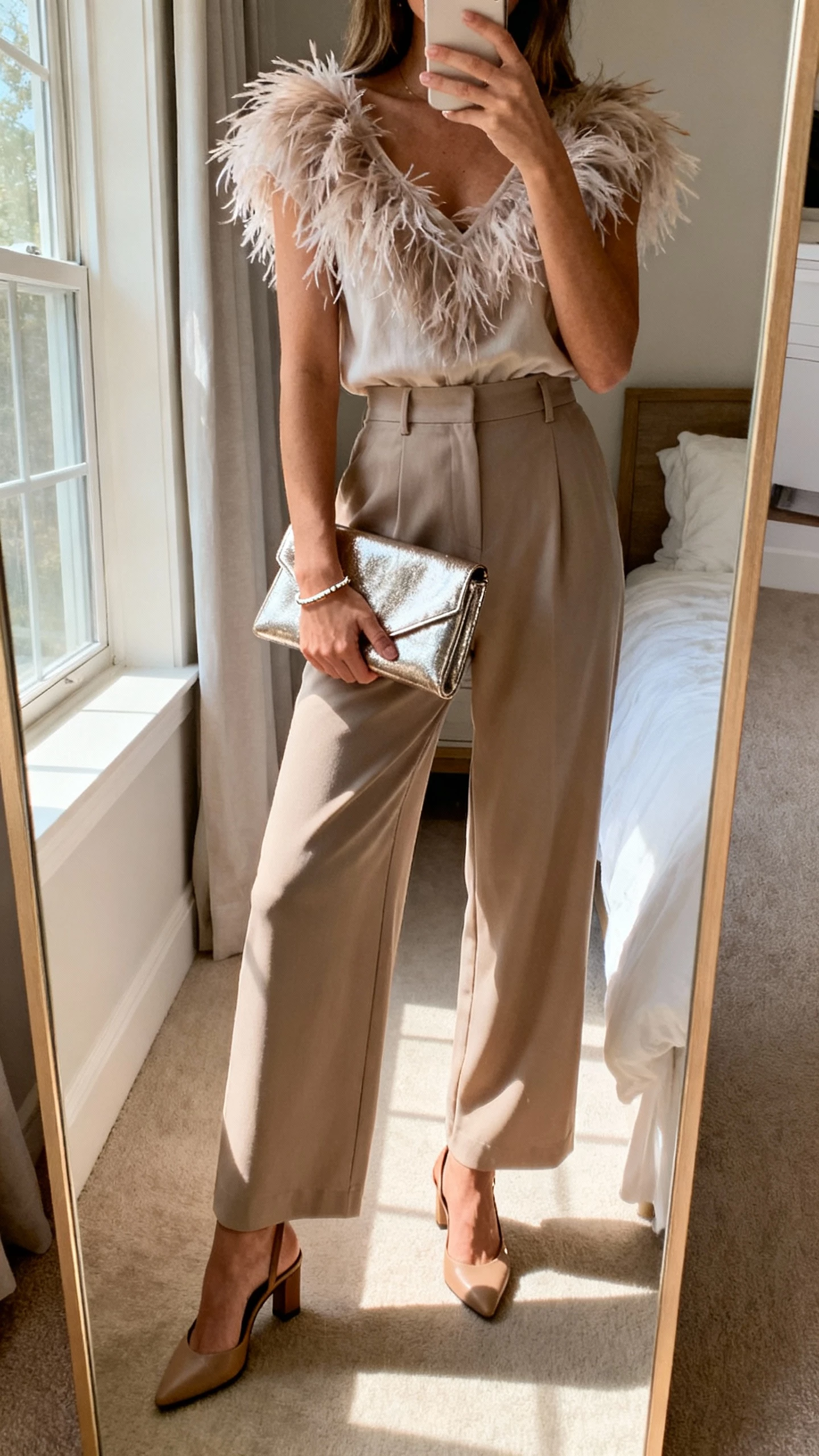 iPhone mirror selfie of a woman in a feather-trimmed top tucked into wide-leg trousers, metallic clutch, slingback heels, subtle bracelet, face not visible, bedroom full-length mirror, afternoon window light, natural iPhone quality.