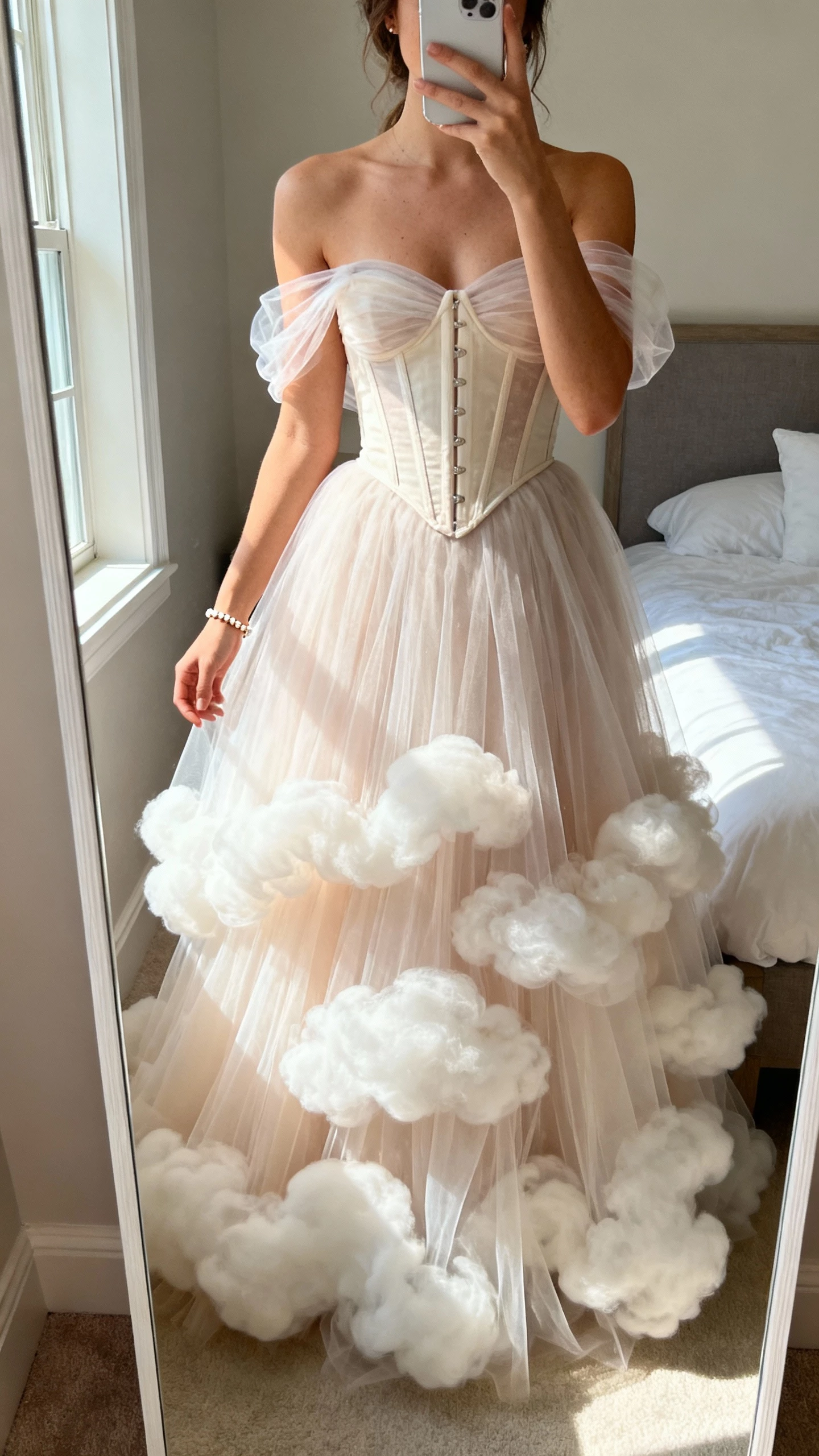 iPhone mirror selfie of a woman in a romantic tulle wedding dress with layered cloud-like skirt, soft corset bodice, sheer tulle straps, dainty bracelet, face not visible, full-length mirror in bedroom, afternoon window light, natural iPhone photo quality