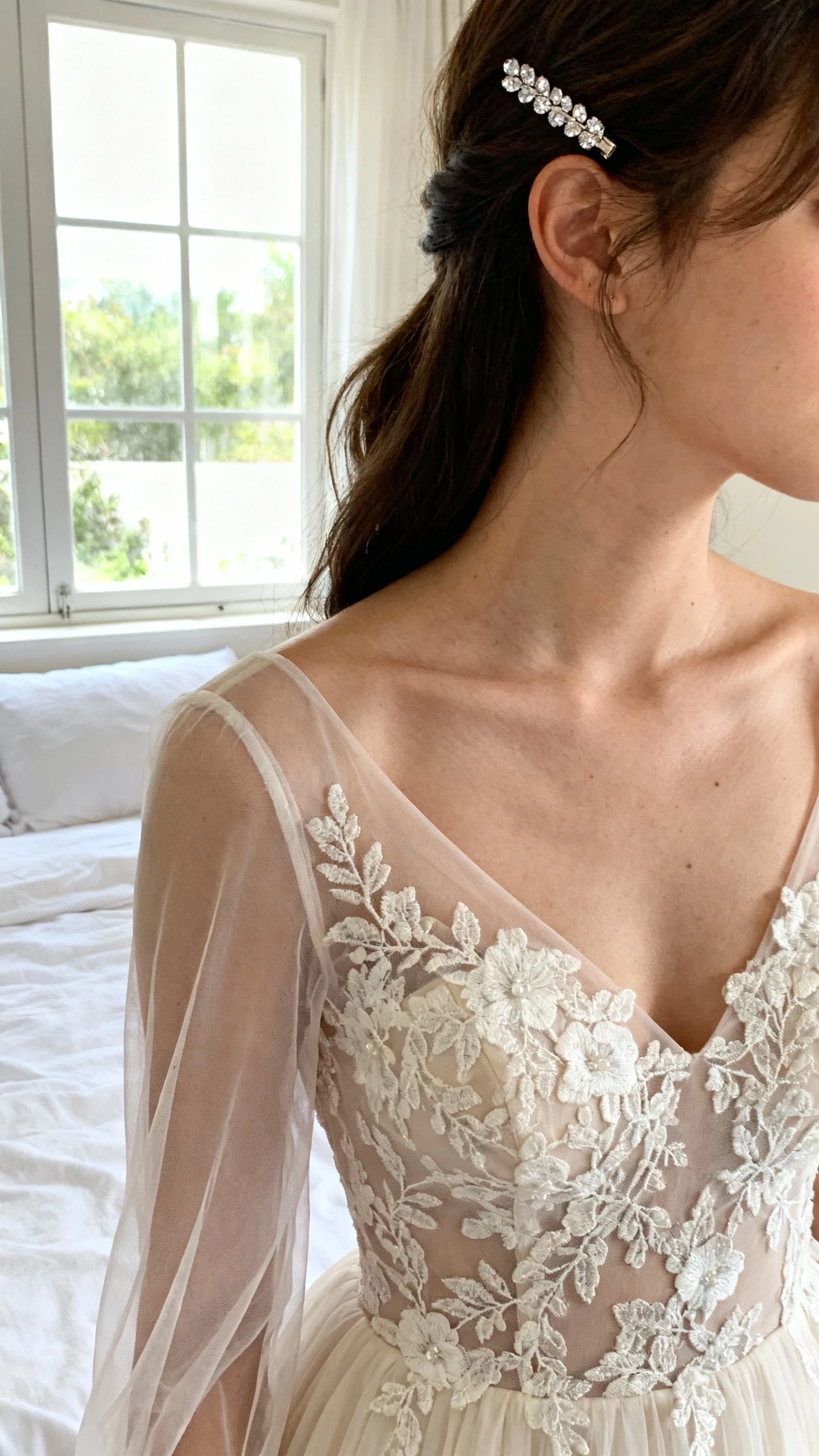iPhone selfie cropped at shoulders showing a woman wearing a romantic lace appliqué fit-and-flare dress with sheer long sleeves, small crystal hairpin, face not visible, bedroom near window, gentle daylight, natural iPhone aesthetic.