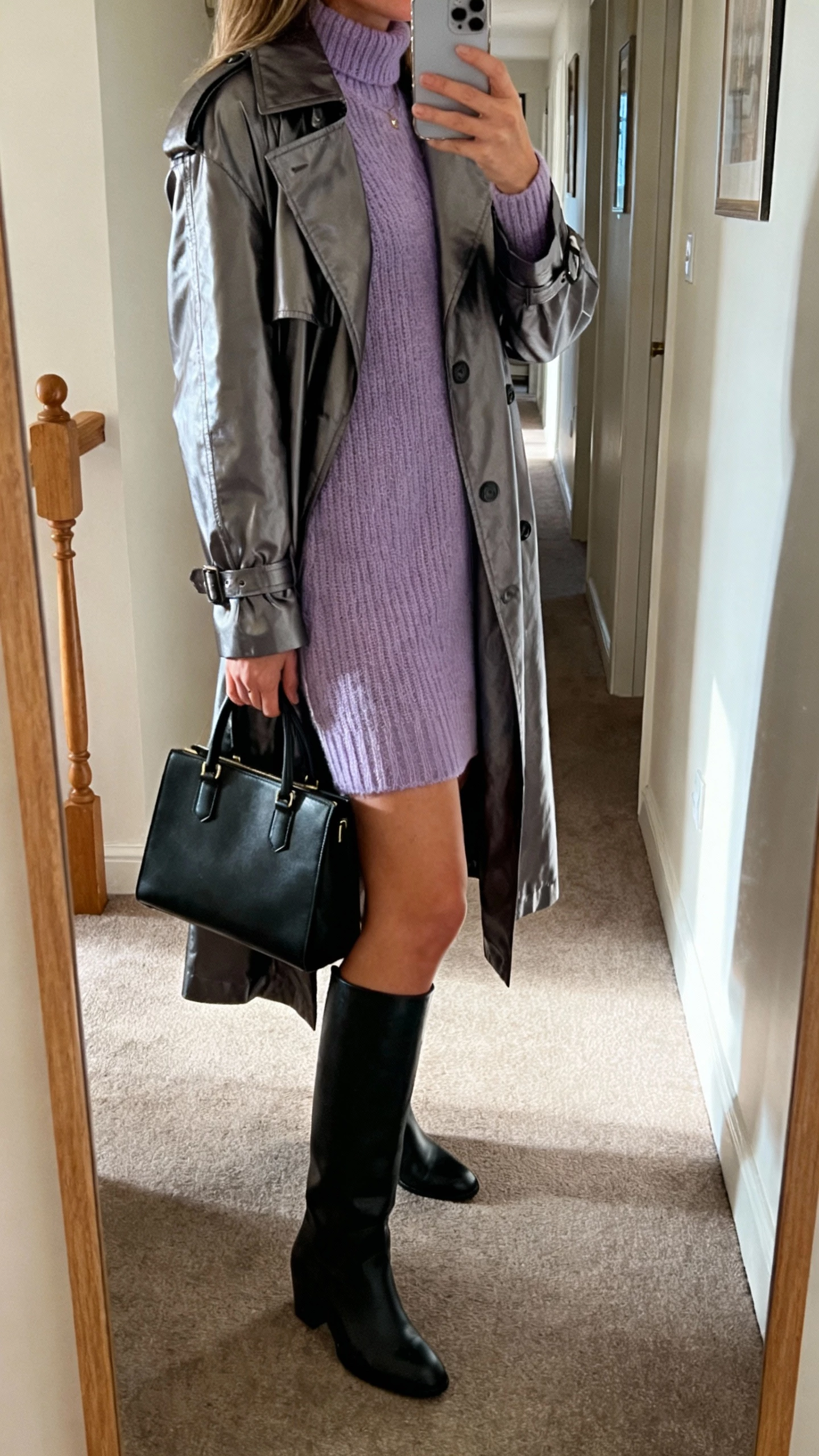 iPhone side-view selfie of a woman in a lavender knit dress under a gunmetal trench, black knee boots, and a structured black handbag, face not visible, apartment hallway mirror with soft morning light, natural iPhone photo quality.