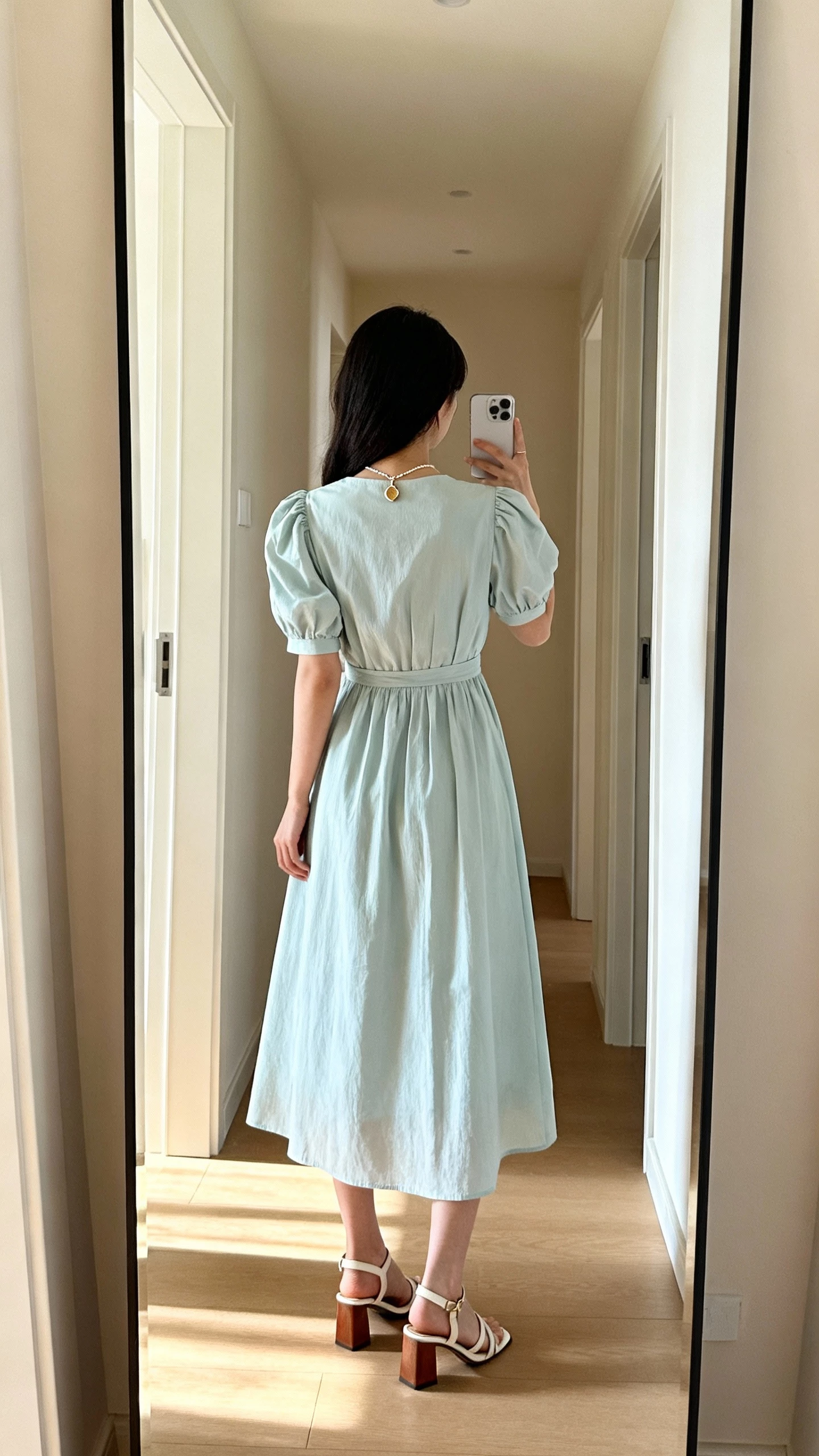 iPhone back-view selfie of a woman in a pastel puff-sleeve midi dress with block-heel sandals and a dainty pendant, face not visible, hallway mirror, breezy morning light, casual iPhone aesthetic