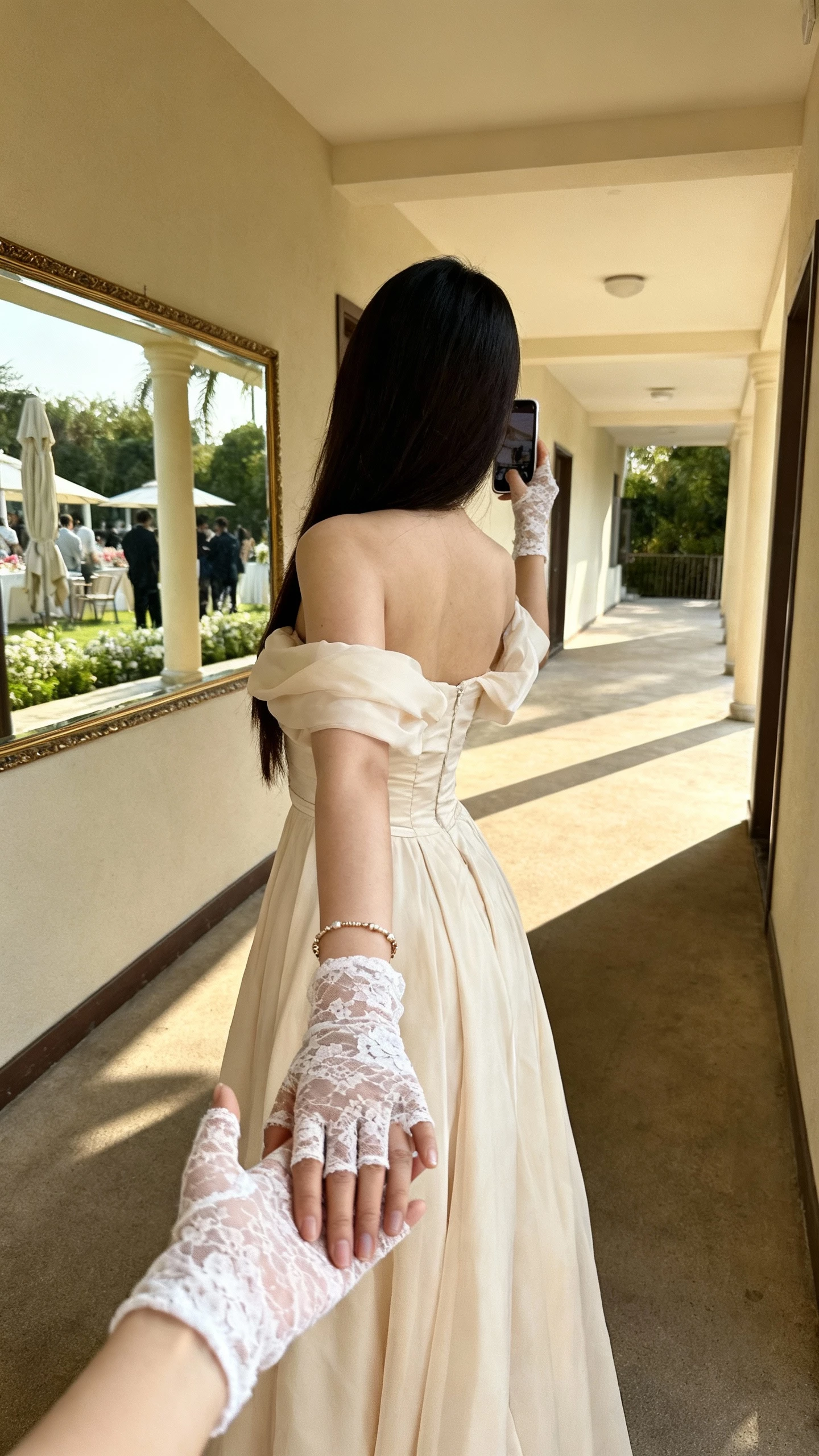 iPhone back-view selfie of a woman wearing fingerless lace mitts with an off-the-shoulder gown, delicate bracelet, face not visible, corridor mirror outside a venue, soft afternoon light, natural iPhone photo quality