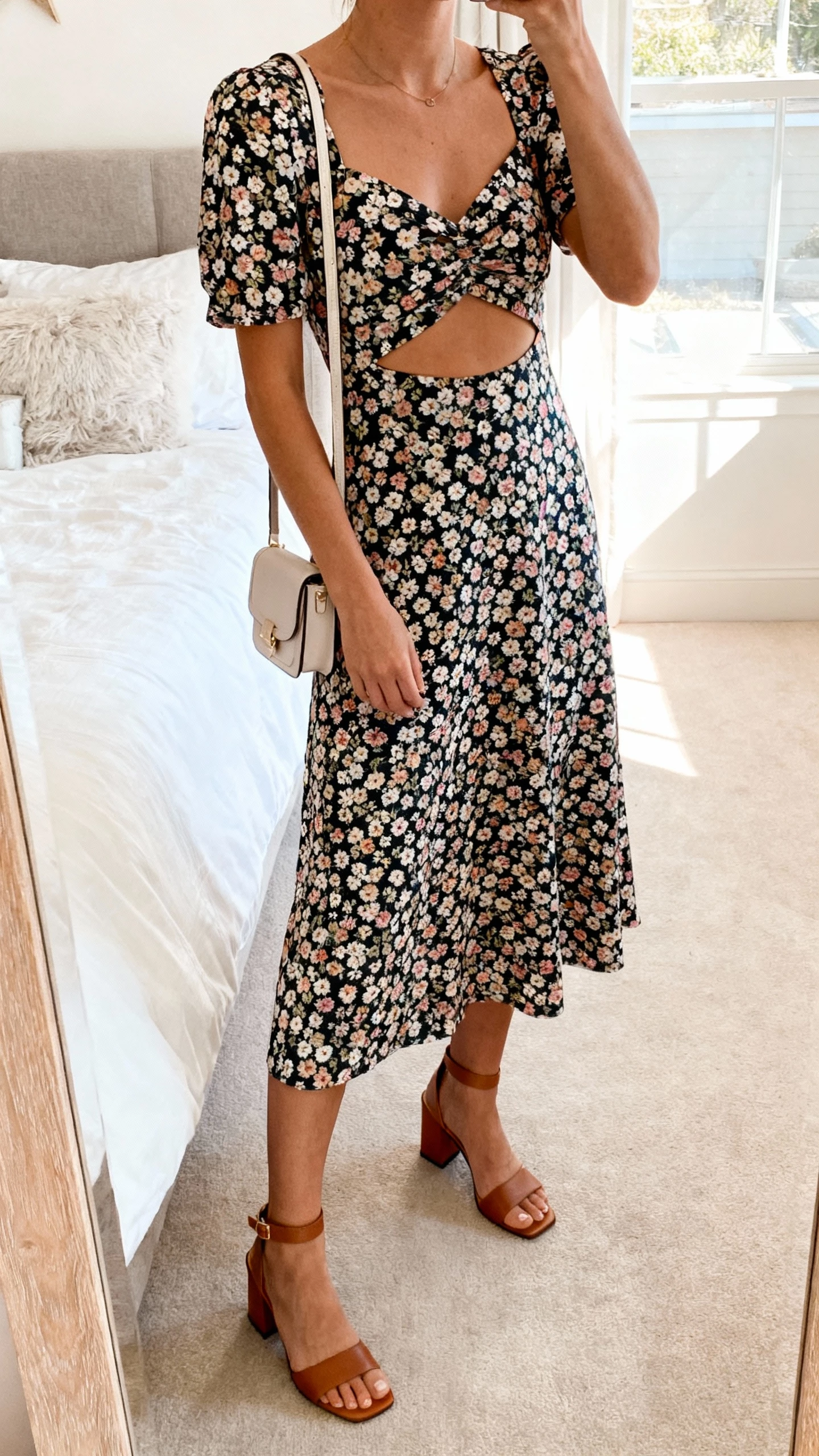 iPhone mirror selfie cropped at neck of a woman wearing a floral cutout midi that’s playful yet polished, block-heel sandals, petite shoulder bag, face not visible, bedroom mirror with soft morning light, natural iPhone aesthetic.