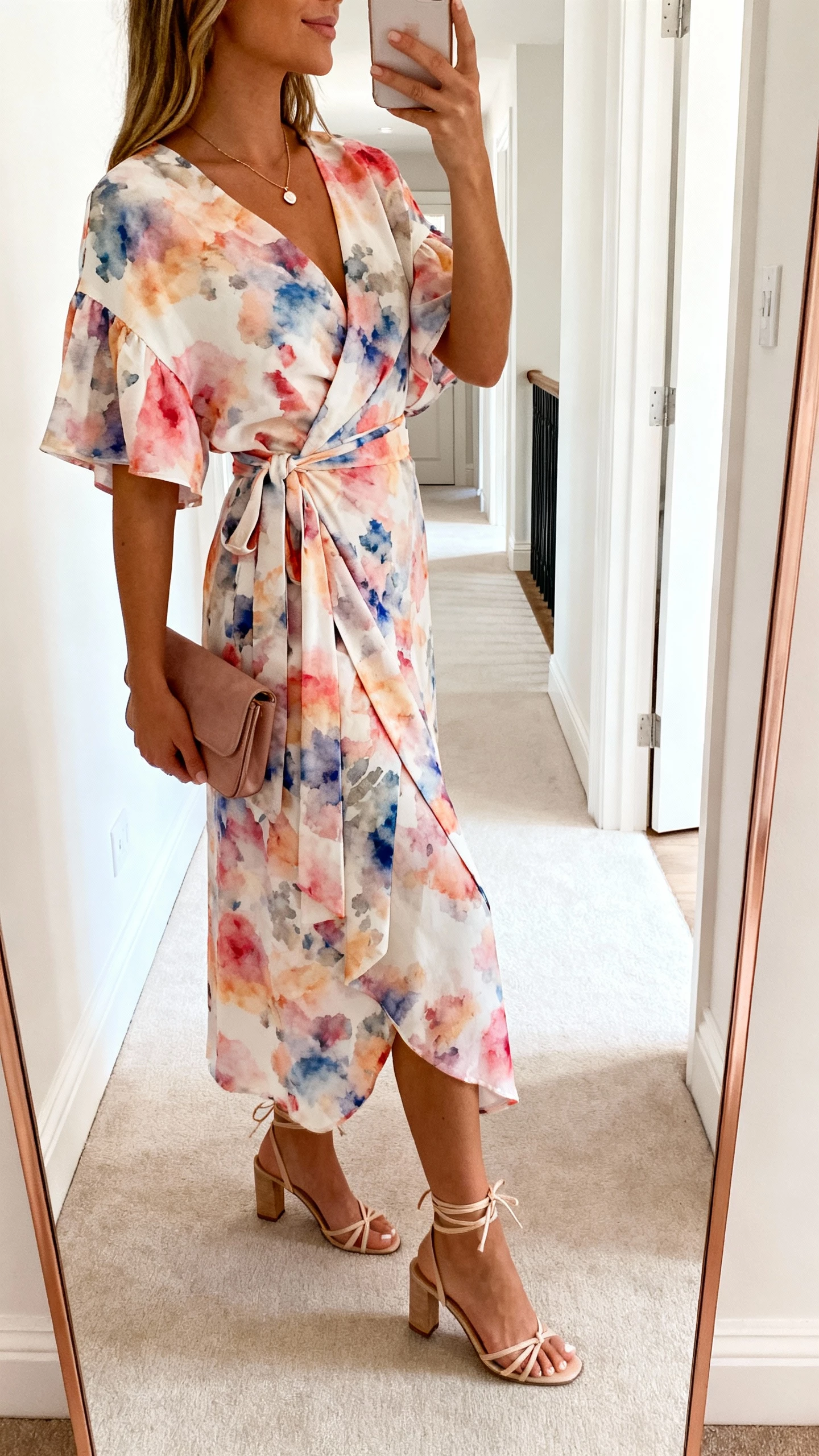 iPhone side-angle selfie showing a woman in a watercolor floral wrap dress with ankle-tie heels, small clutch, dainty pendant, face not visible, hallway mirror in a bright entryway, natural daylight, casual iPhone aesthetic
