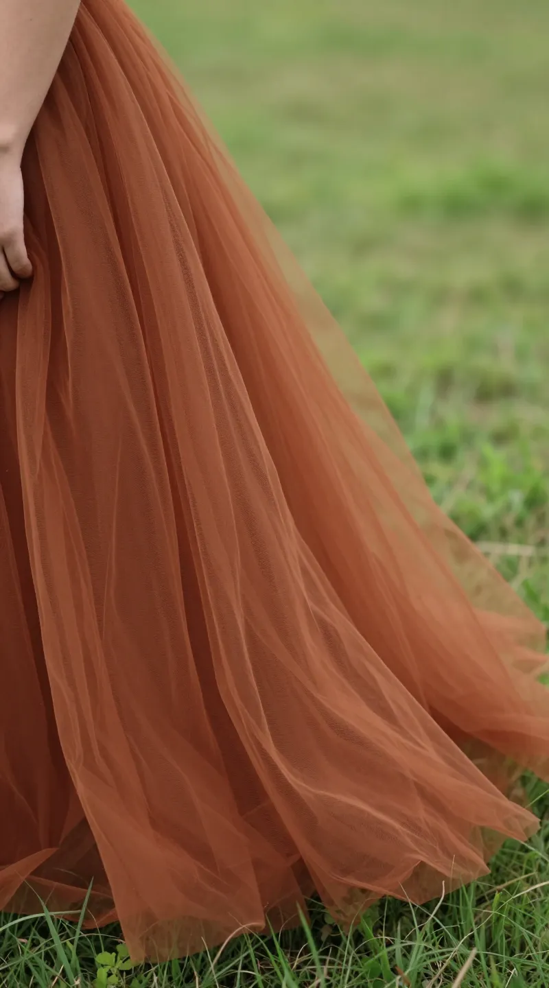 **Closeup of bride’s rust tulle skirt flowing in meadow breeze**