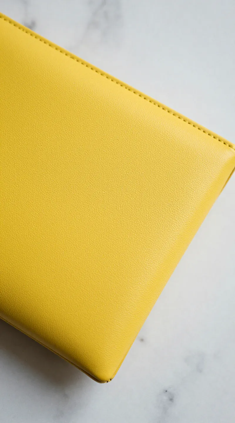 **Closeup of a sunshine yellow clutch on marble surface**