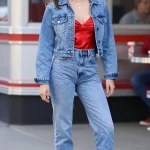 **Image Prompt:** "A stylish young woman confidently poses in a nostalgic yet fresh 90s-inspired denim-on-denim outfit, channeling Rachel Green’s iconic look. She wears a light-wash cropped denim jacket layered over a bold red satin cami, tucked into matching high-waisted light-wash jeans. The jeans are cuffed once to showcase her white chunky platform sneakers (or optional red mules). Her playful accessories include mini heart-shaped sunglasses and delicate gold jewelry. The background is a bright urban setting—perhaps a lively street or retro diner—with soft natural lighting enhancing the fun, flirty vibe. The composition is a full-body shot, capturing the effortless coolness of the outfit, with a slight motion blur in her hair or jacket for a candid, dynamic feel."