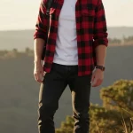 **Image Prompt:** *A rugged yet stylish young man posing confidently in an adventure-ready outfit, standing against a scenic outdoor backdrop with soft natural lighting. He wears a red-and-black checkered flannel shirt left unbuttoned over a fitted white tee, with the sleeves casually rolled halfway up his forearms. His dark skinny jeans are slightly cuffed at the hem to showcase a pair of sturdy hiking boots or classic high-top sneakers. His relaxed yet confident stance suggests an outdoorsy vibe—perhaps near a forest trail or a campsite, with a warm, golden-hour glow enhancing the rugged charm of the ensemble. A hint of adventure accessories (like a leather wristband or a backpack slung over one shoulder) completes the look, making it effortlessly cool and Valentine’s Day-date-worthy.*
