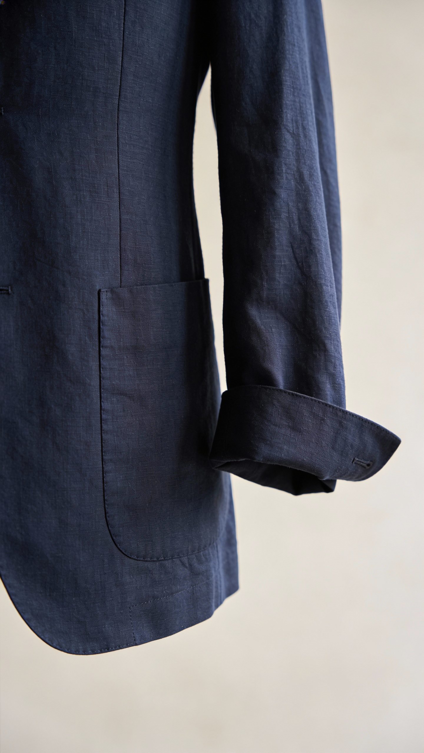 **Closeup of a navy linen suit with rolled sleeves**