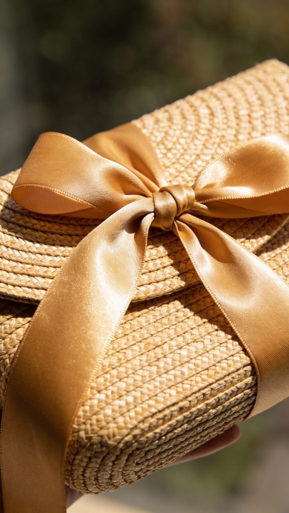 **Detailed shot of a woven straw clutch with silk ribbon tie**