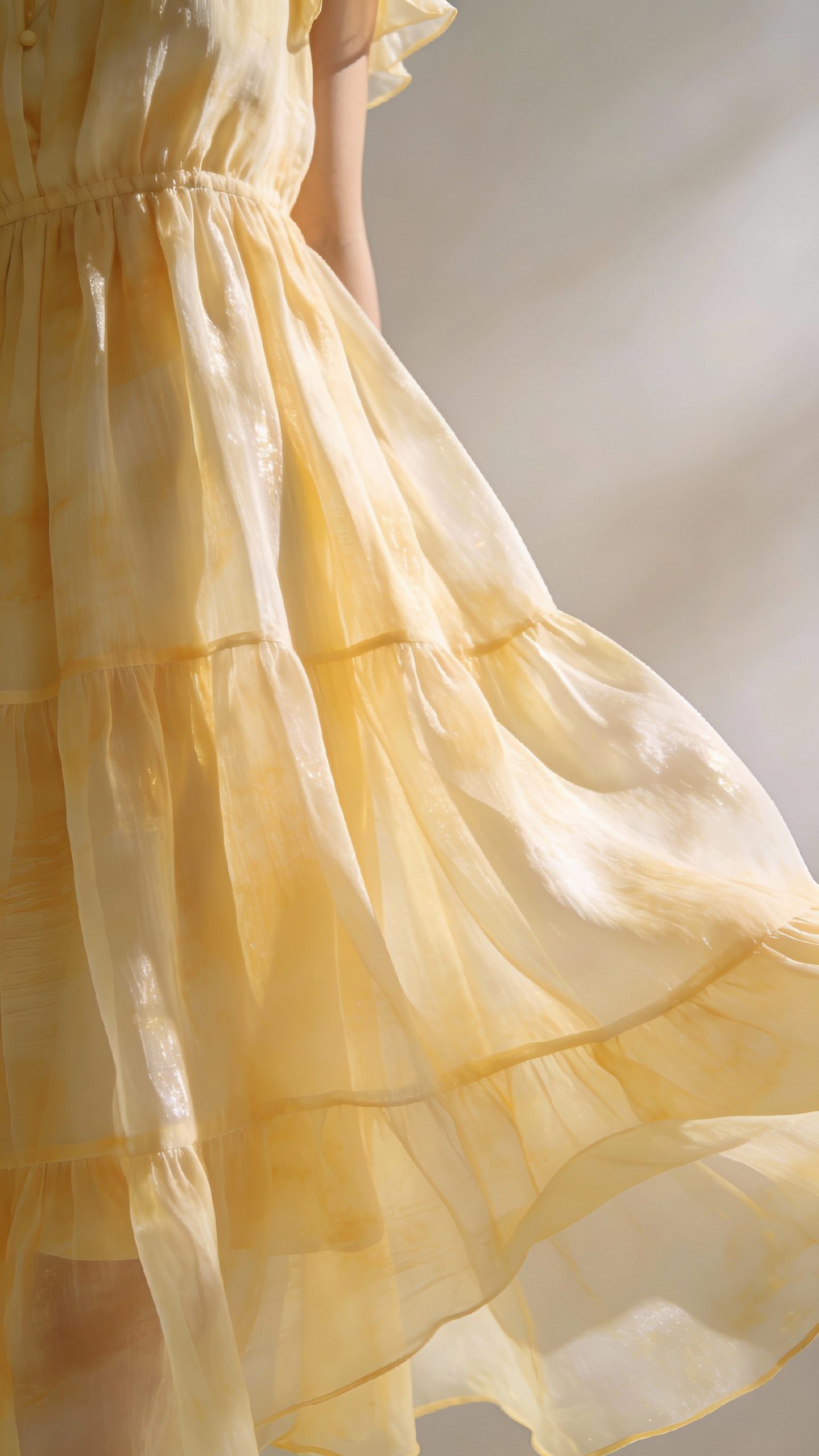 **Closeup of a flowy chiffon sundress in pastel yellow**
