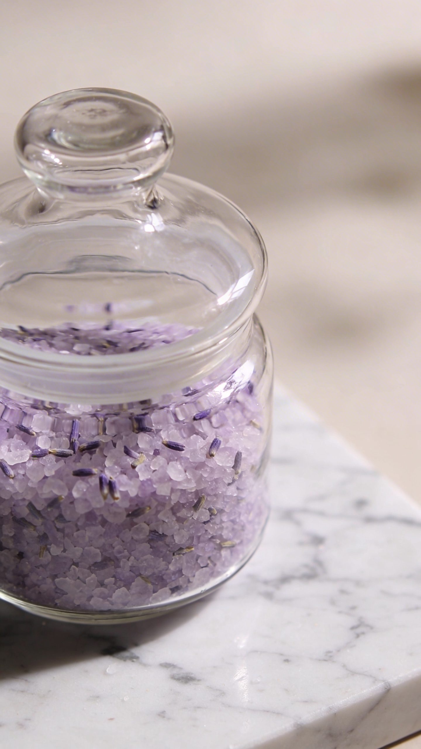 closeup glass jar of lavender bath salts on marble