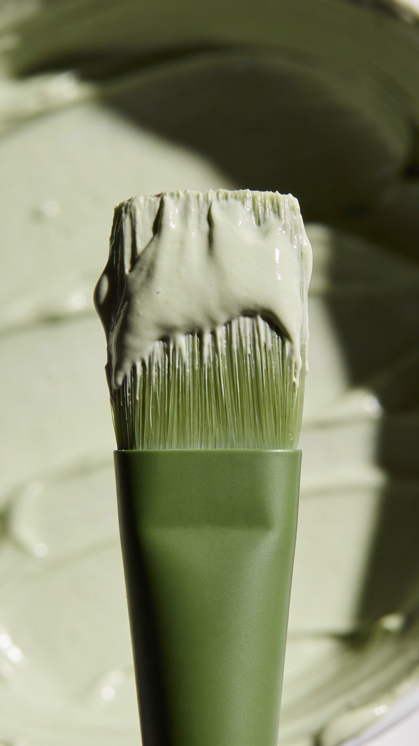 single green clay mask brush with creamy mixture on bristles
