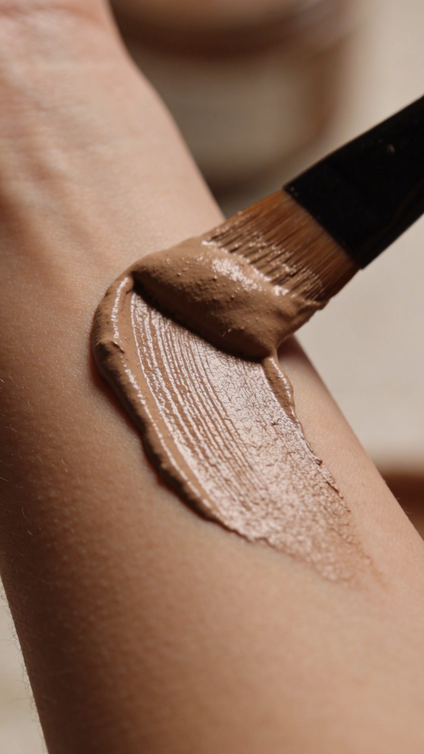 closeup of clay body mask brushed on forearm skin