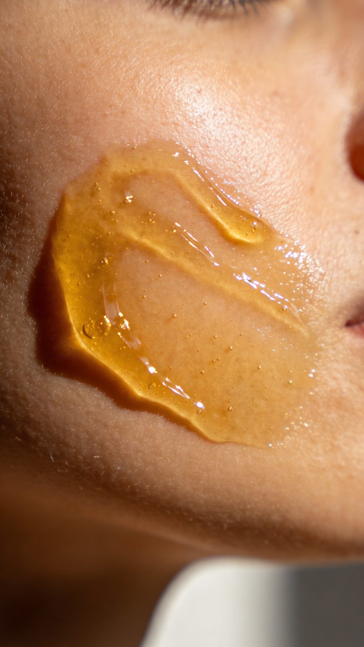 closeup of honey face mask on single cheek, soft daylight