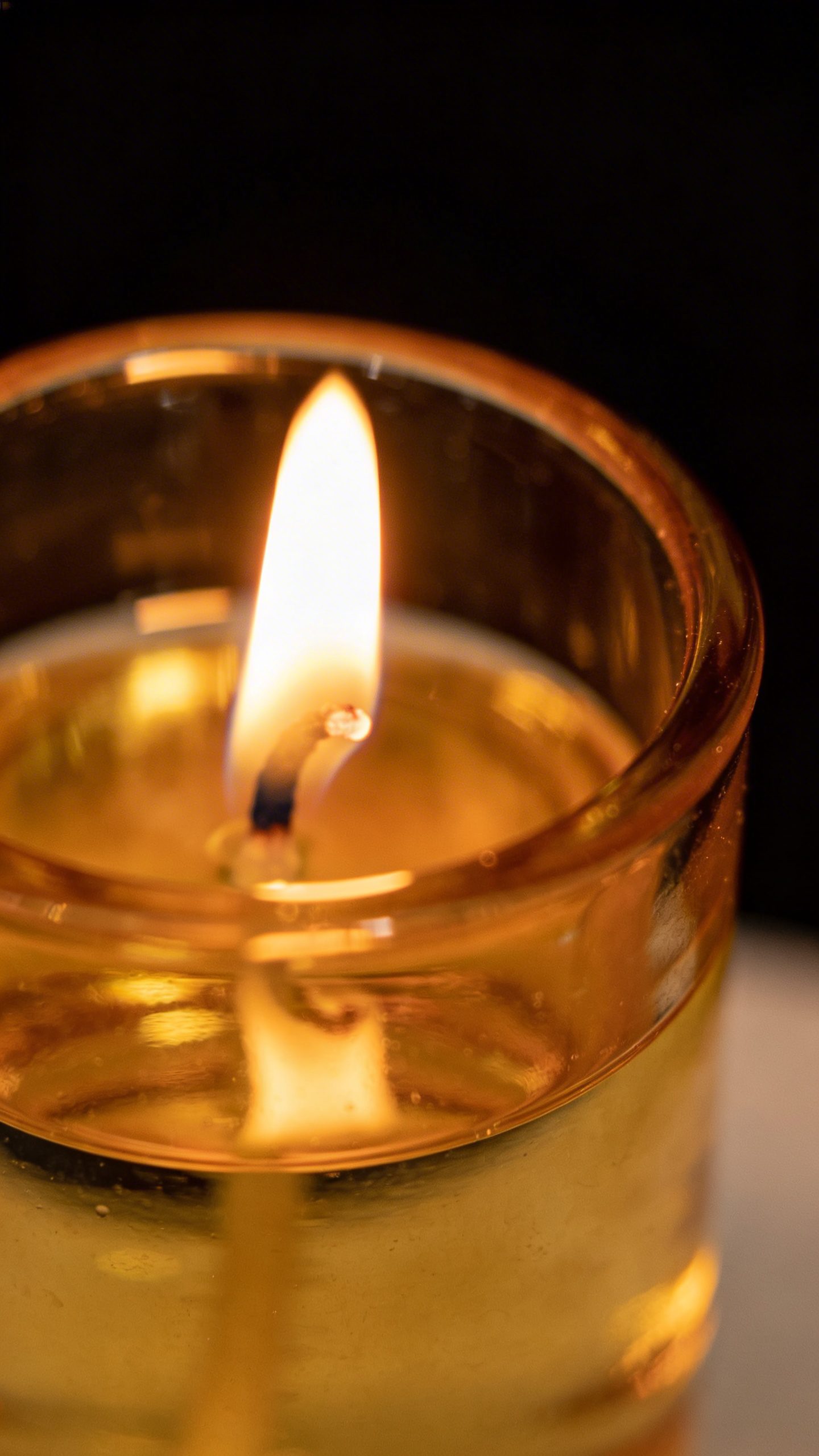 amber glass candle, soft flame, matte black background