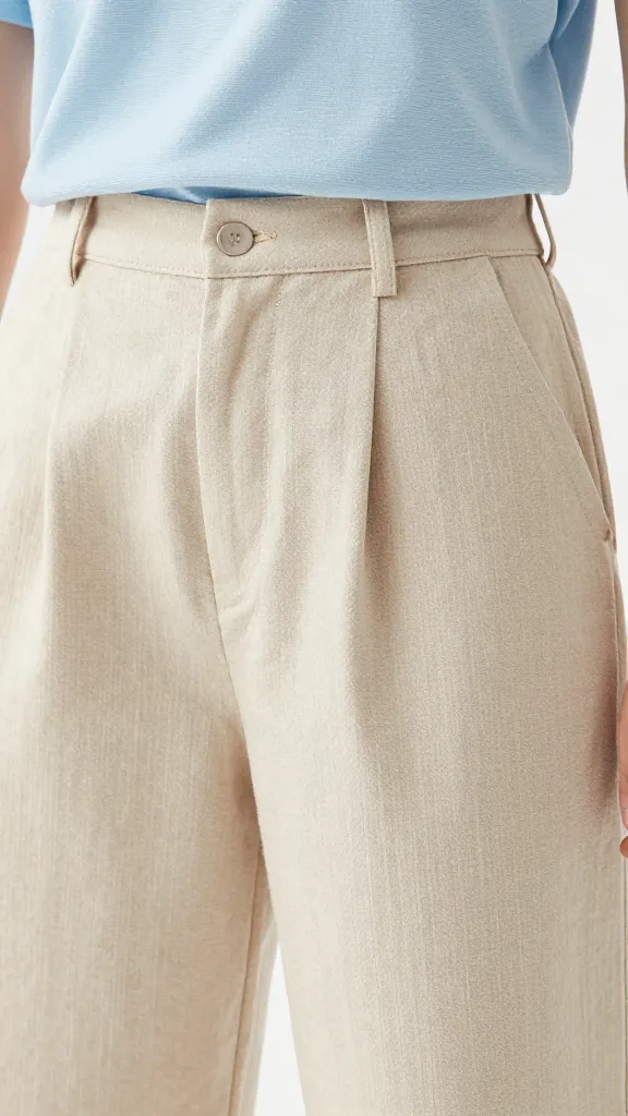 A close-up shot of a summer school outfit focusing on fabrics: a linen-blend wide-leg pant in pale sand color paired with a light blue moisture-wicking tee, showing texture and drape of the fabrics.